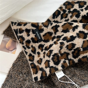 Detailed close-up of wool-blend leopard print scarf showing fine knit texture and label