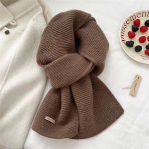 Detail of coffee brown knitted wool scarf texture with brand tag on white wool coat