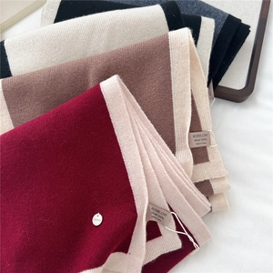 Detailed close-up of 100% wool knitted scarves with premium contrast stitching and brand labels