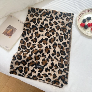 Detailed view of leopard print wool blend scarf with woven brand tag on soft fabric
