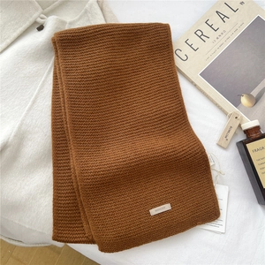 Detail of soft brown knitted wool scarf texture with brand tag on minimalist background