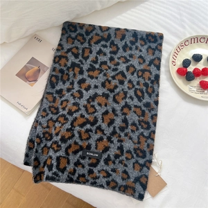 Detail of wool leopard print scarf with brand label and thick knitted texture