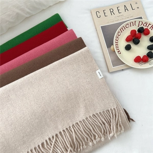 Multiple colors of 100% pure wool scarves with fringe on a minimalist white table