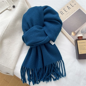 Detail shot of a dark peacock blue 100% wool knitted scarf with soft fringe tassels
