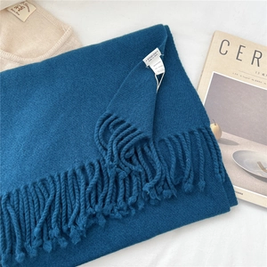 Detail of 100% wool scarf showing soft knit texture, fringes, and the product brand label