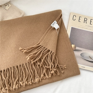 Detail of solid dark camel wool scarf showing fringe tassels and fine knit texture