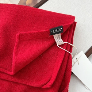 Detail of red 100% wool scarf showing high-quality knit texture and product label