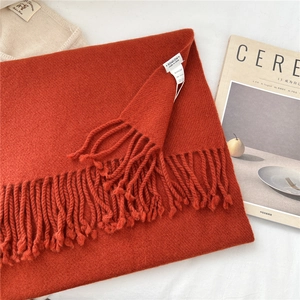 Detail of burnt orange 100% wool scarf showing soft knit texture and fringe edges