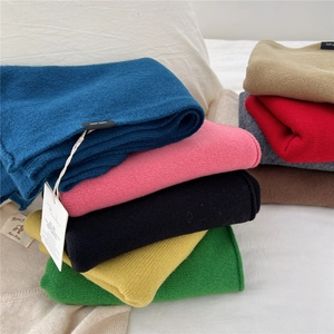 Stack of colorful 100% wool scarves in diverse solid colors with premium knitted texture