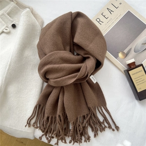 Detail of a brown wool scarf with twisted fringe and 100% wool composition tag