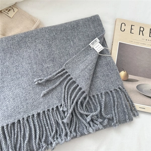Detail of gray 100% wool scarf featuring fringe trim and soft twill weave texture