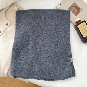 Close-up of 100% pure wool dark grey knit scarf with soft texture and material label