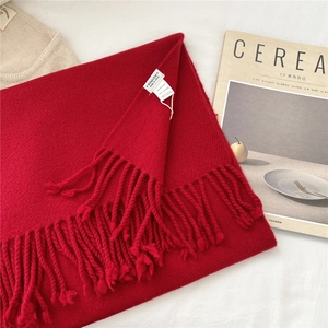 Detail of red wool scarf featuring 100% wool wash label and soft fringed edges