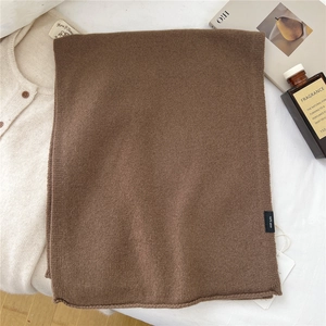 Close-up of 100% pure wool scarf fabric showing a detailed soft knit texture in brown