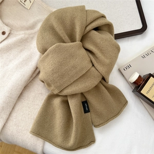 Detailed view of camel 100% wool scarf showing soft knit texture and material tag