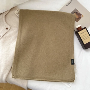 Close-up of camel wool scarf showing 100% wool label and soft knit texture detail
