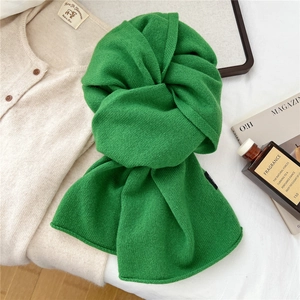 Close-up of vibrant green 100% wool knit scarf with soft ribbed texture and wool label