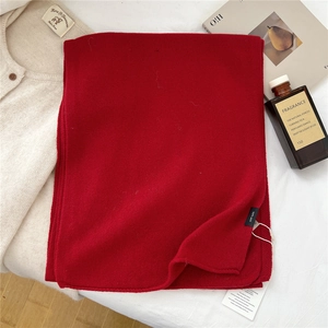 Close-up of a premium deep red 100% wool scarf with detailed knitting and brand tags