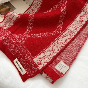 Detailed macro of red knit scarf texture featuring white patterns and product care label