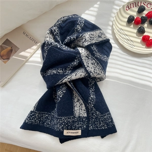Detail showing soft knit navy blue and white geometric pattern scarf with woven brand tag