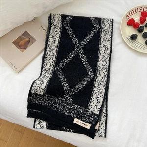 Macro view of diamond-patterned knitted scarf with ACT SURPRISE brand tag detail
