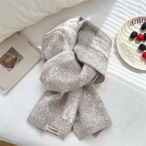 Close-up of thick grey and white diamond knit scarf with ACT SURPRISE fabric label