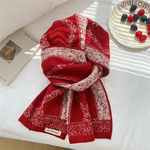 Macro detail of red and white jacquard knit scarf showing thick soft texture and brand label