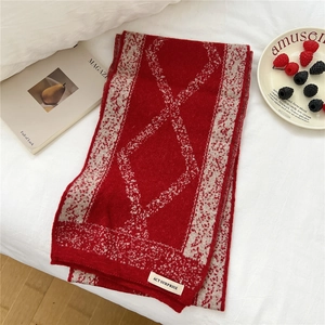 Detail of red and white diamond pattern knit scarf with ACT SURPRISE brand label