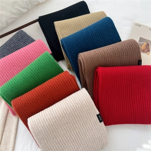 Detailed top view of 100% wool knitted scarves in multiple vibrant colors with woven labels