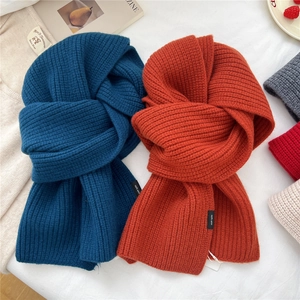 Chunky knit 100% wool scarves in teal and orange displayed on soft white fabric