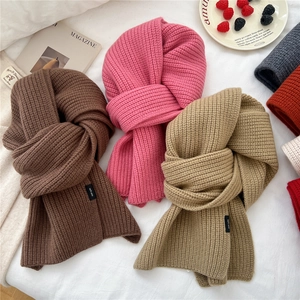 Flat lay of colorful 100% wool knit scarves with thick texture and cozy autumn aesthetic