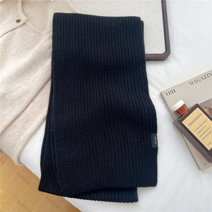 Detailed close-up of thick ribbed knit texture on a 100% black wool winter scarf