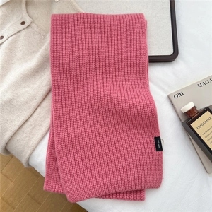 Close-up of pink 100% wool knitted scarf showing thick texture and authentic quality label