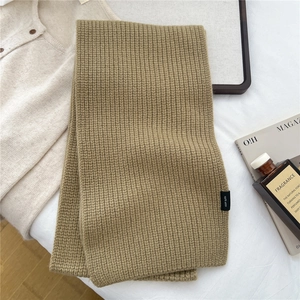 Close-up of camel wool scarf showing ribbed knit texture and 100% wool material label