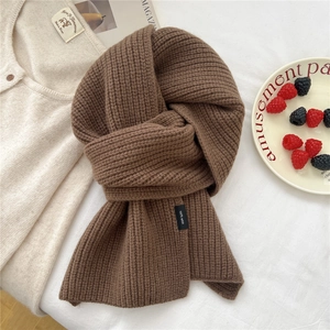 Detail of a brown ribbed knit scarf showing the 100% wool label on textured fabric