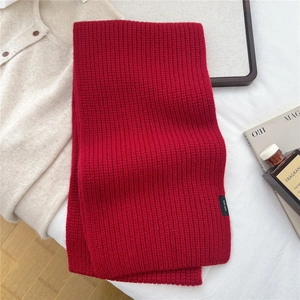 Macro detail of the 100% pure wool red knitted scarf showing classic ribbed texture