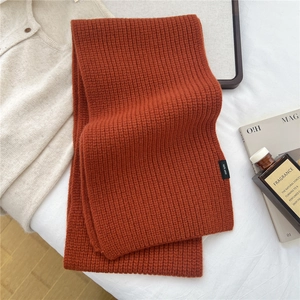 Close-up of caramel orange 100% wool knit scarf with authentic fabric quality label