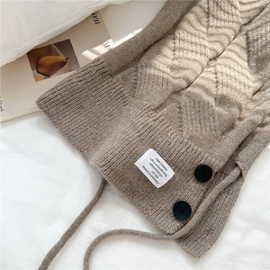 Macro shot of khaki cable knit balaclava with black buttons and a white woven label