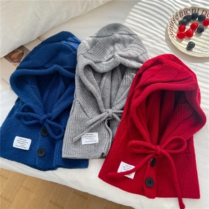 Detail of knitted balaclava hats in navy, grey, and red with buttons and drawstrings