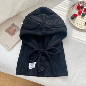 Detailed close-up of a black knit balaclava with decorative buttons and woven logo tag