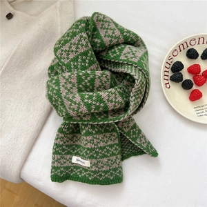Detail of 100% wool knit scarf featuring green and grey geometric patterns and texture
