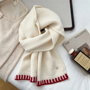 Detailed knit of white wool scarf featuring red stripes and a gold metal button buckle
