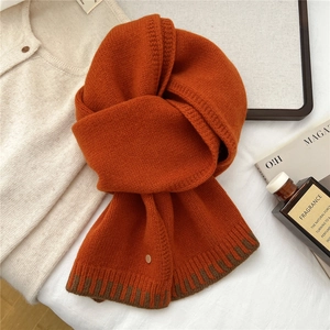 Detailed knit texture of a caramel wool scarf with dark brown contrast and metal button
