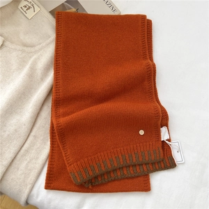 Detailed texture of thick orange wool scarf with dark brown stripes and gold button