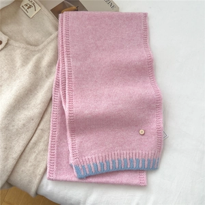 Detail of pink wool knit scarf with blue ribbed edge and small gold brand tag