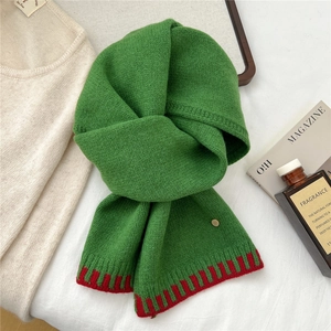 Close-up of chunky green knit wool scarf with red color-block detail and gold emblem