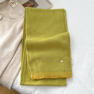 Detail of lime green wool knit scarf with ribbed edge and metal D-letter ornament