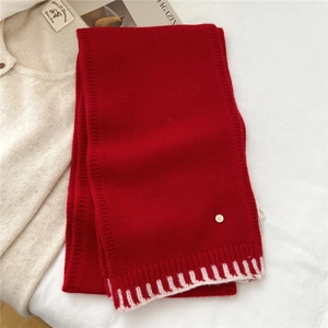 Detailed view of red wool scarf with color-block stitching and metal D-letter emblem