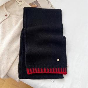 Close-up of black knitted wool scarf with red stripes and premium metal letter D charm
