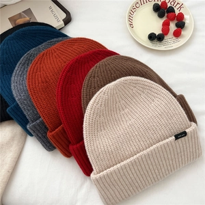 Detailed view of assorted knitted wool beanies with high quality 100% wool material tag
